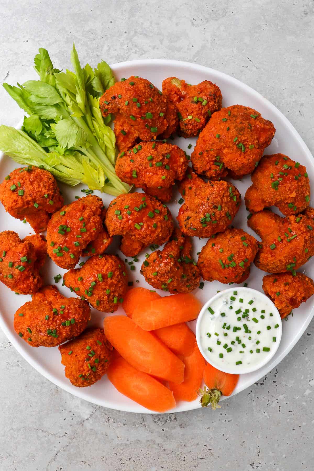 Buffalo broccoli wings on a plate with celery, carrots and ranch.