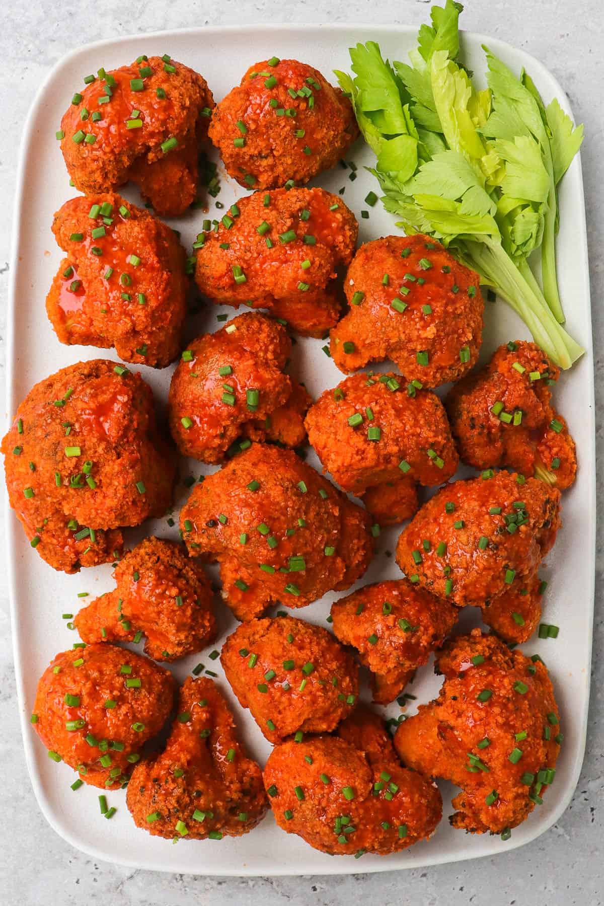 Buffalo broccoli wings one platter with celery leaves.