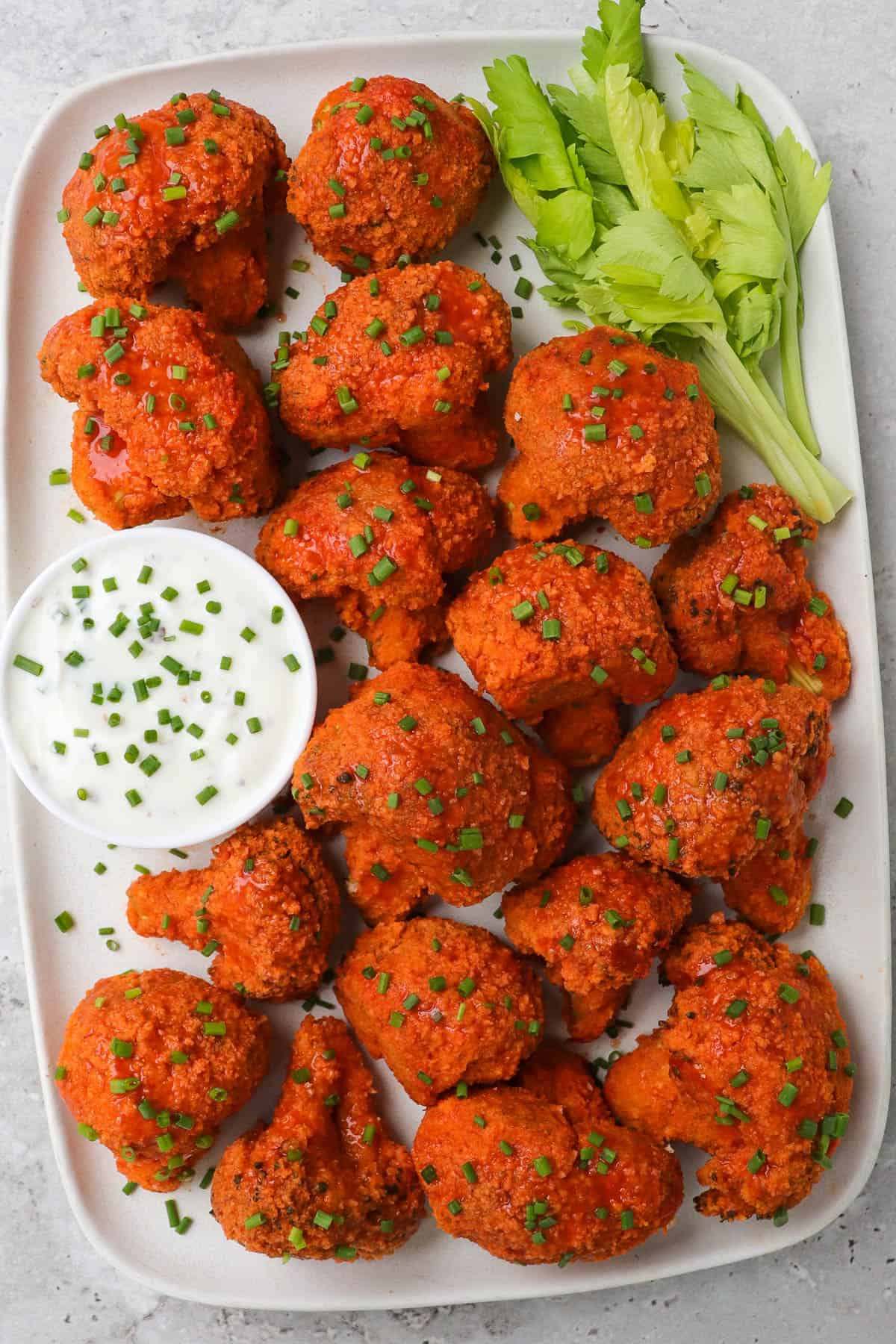 Buffalo broccoli wings one platter with celery leaves and ranch.