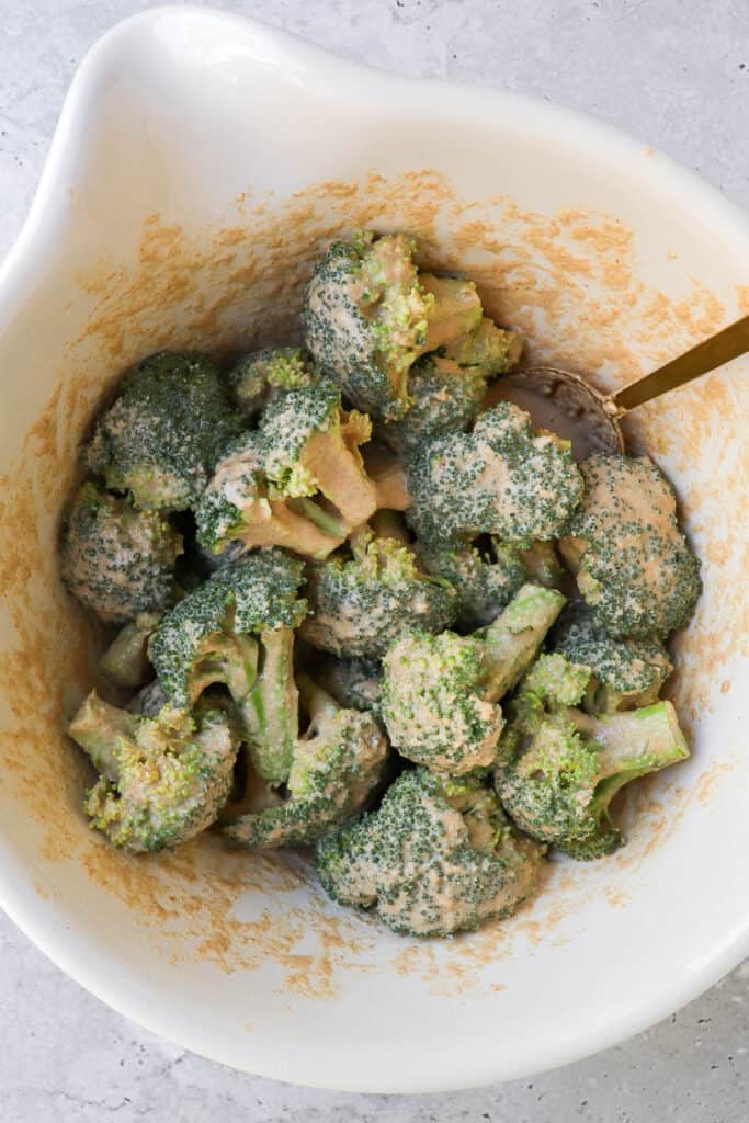 Broccoli wings in a bowl coated in buffalo batter.