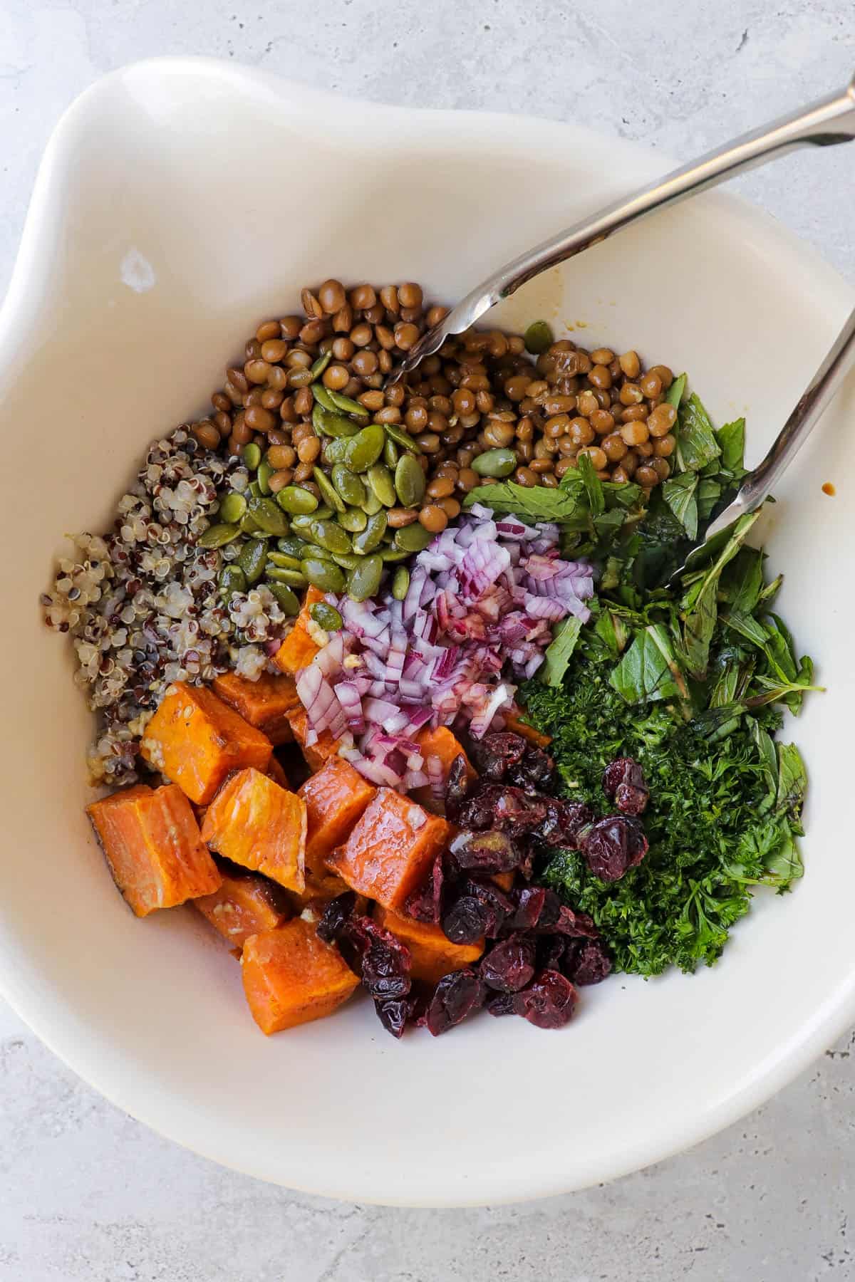 Salad ingredients in mixing bowl with tongs.