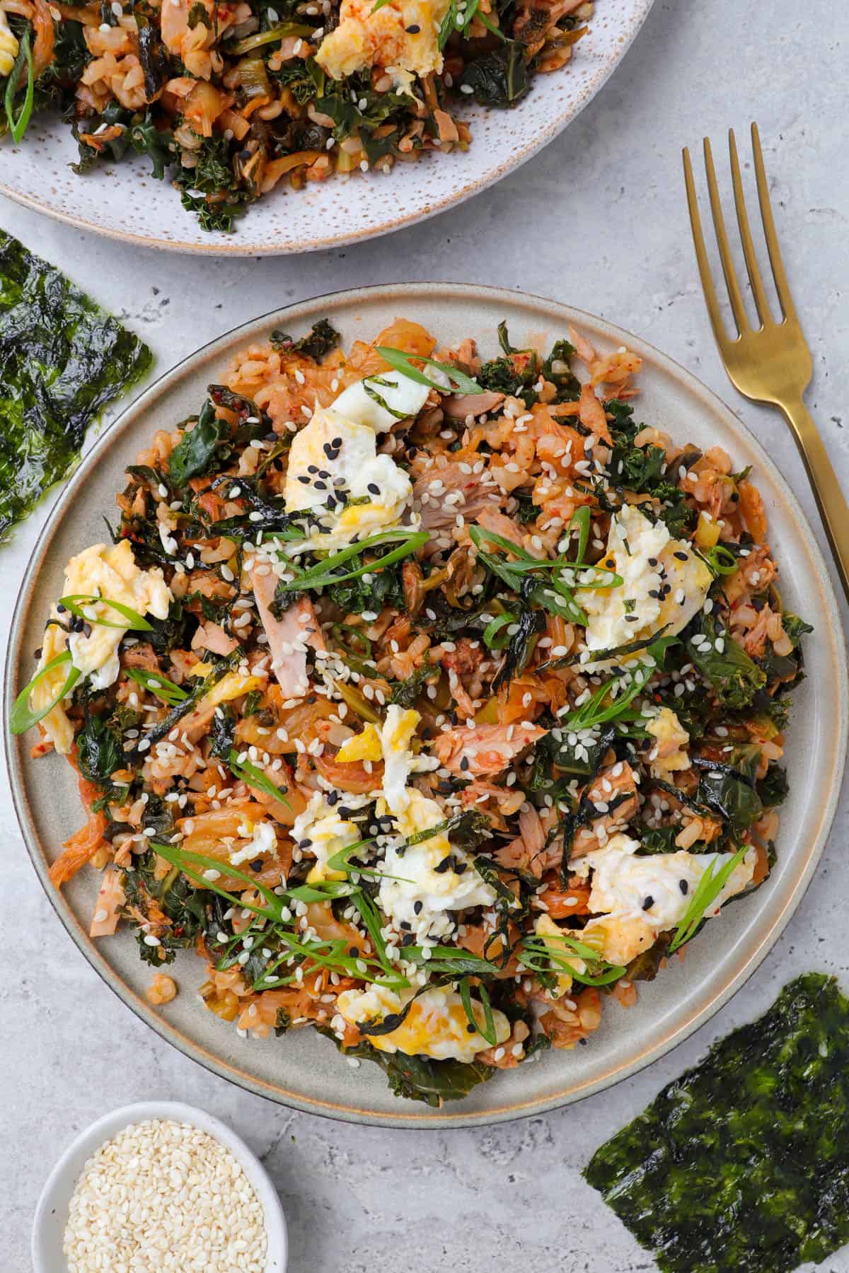 Fried rice on plate with fork, seaweed and sesame seeds on the side.