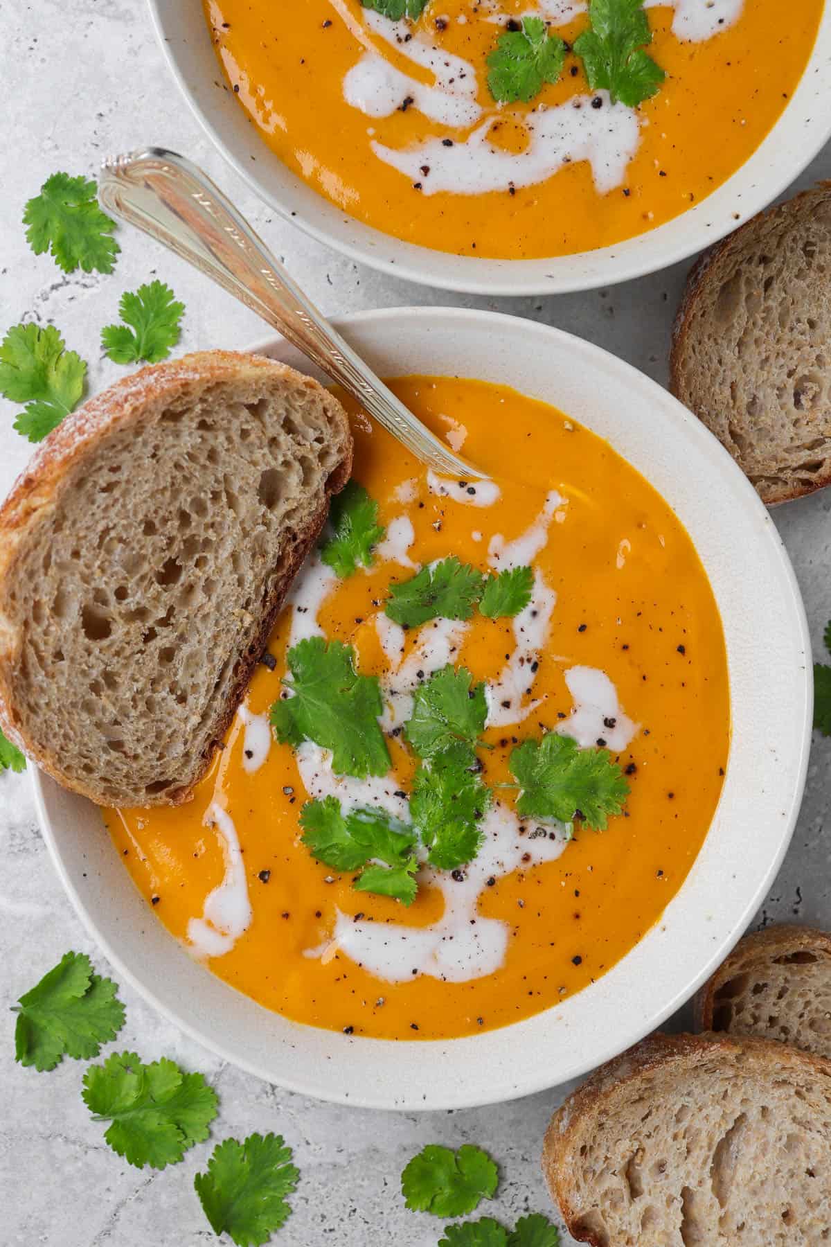 Carrot swede soup in a bowl with sourdough and spoon.
