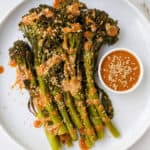Tenderstem broccoli on a plate with miso sauce drizzled on top.