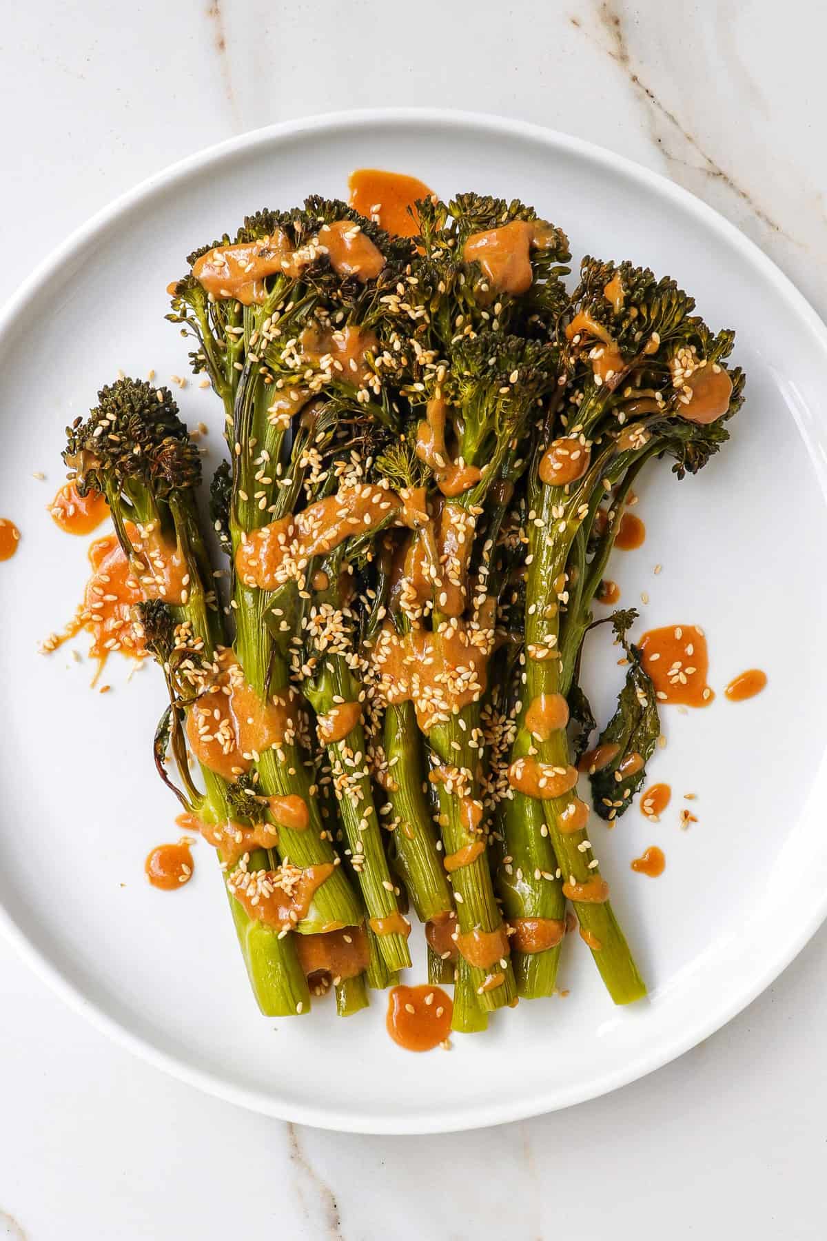 Tenderstem broccoli on a plate with miso sauce drizzled on top.