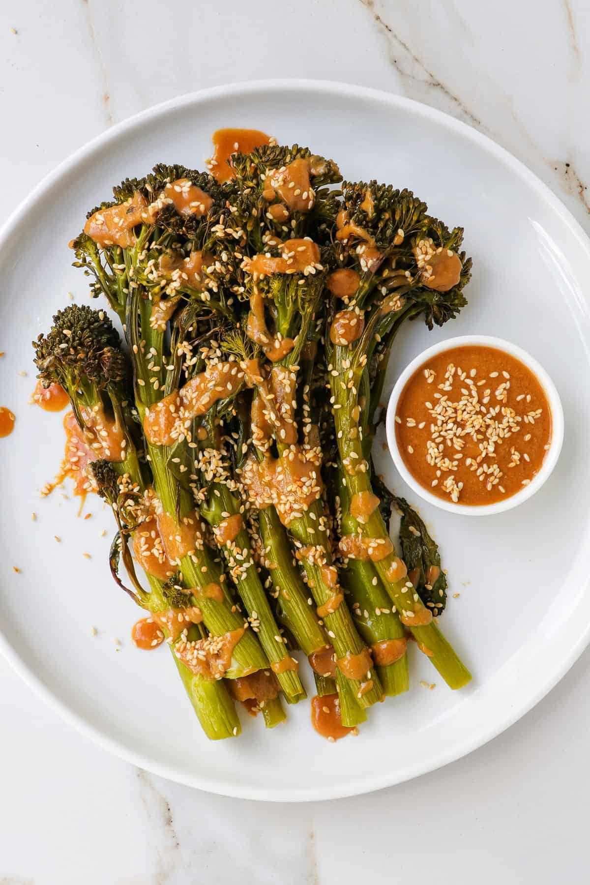 Tenderstem broccoli on a plate with miso sauce drizzled on top.