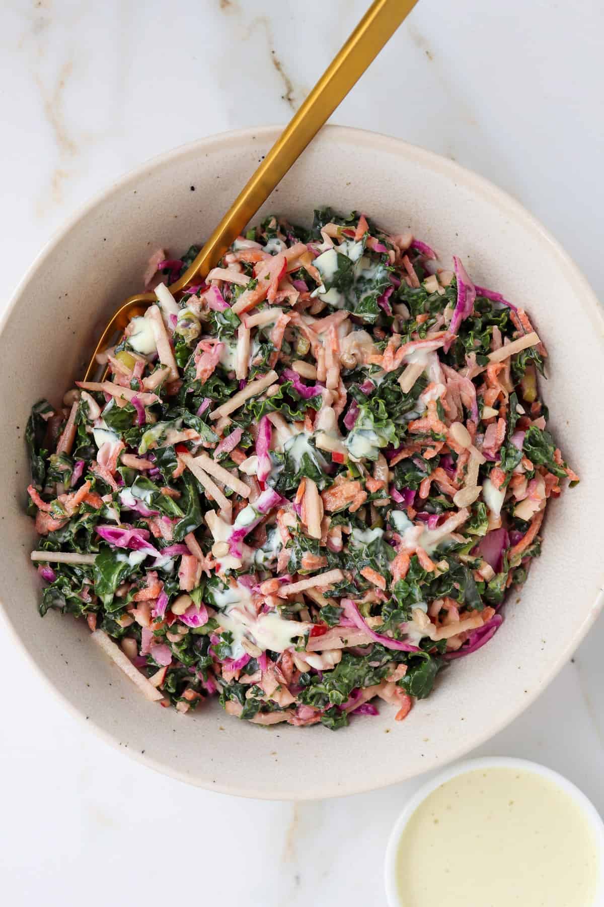 Kale and apple slaw served in a bowl with yoghurt dressing drizzled on top.