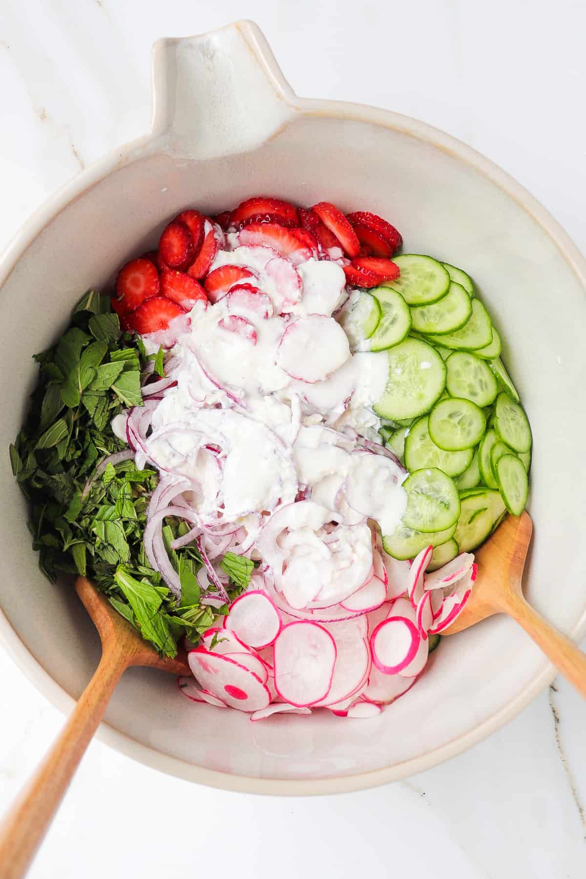 Salad ingredients in a large mixing bowl with the feta yogurt dressing poured in the middle.
