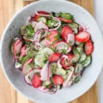 Salad served in a bowl on a wooden board.