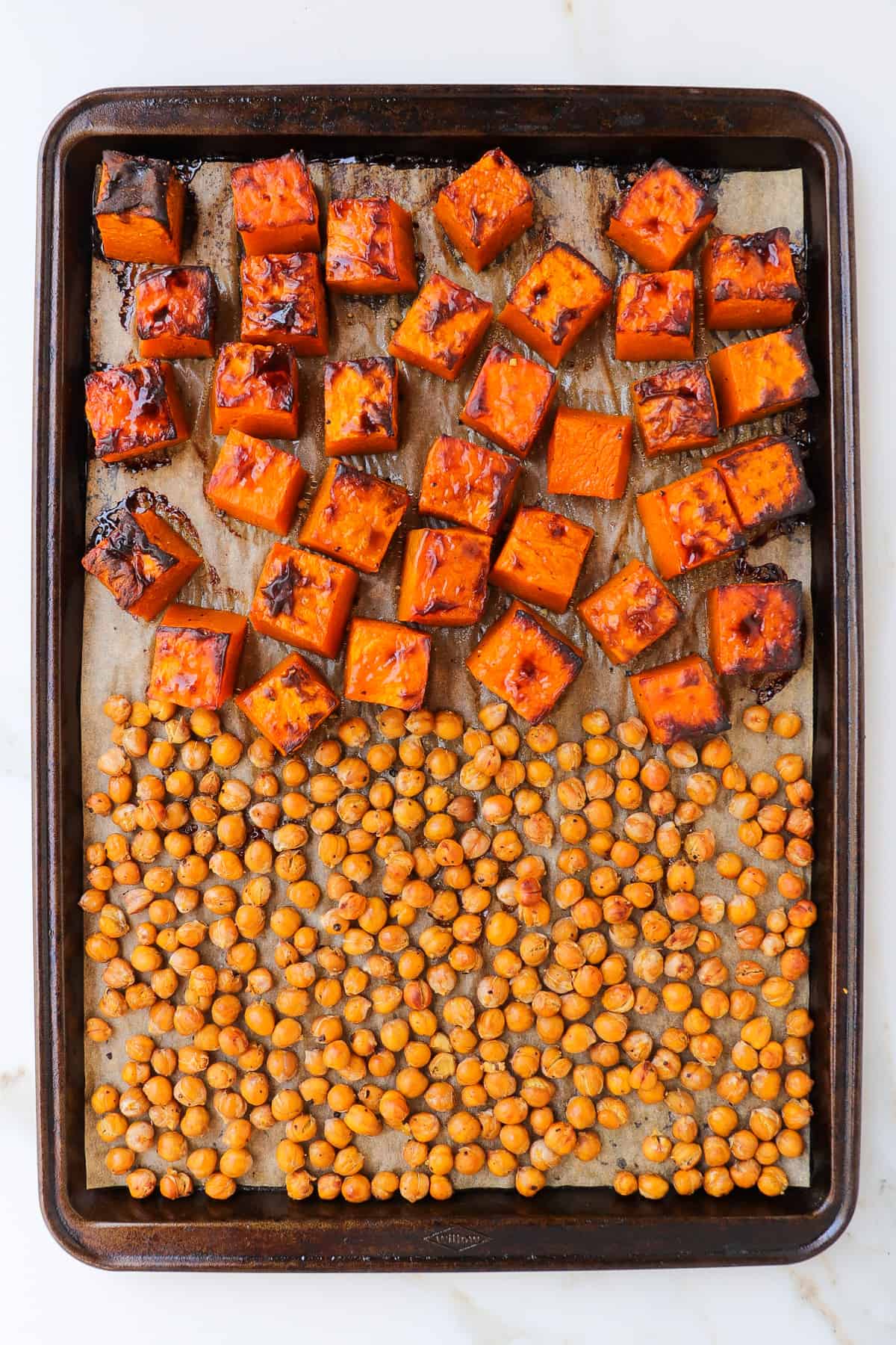 Roasted pumpkin and chickpeas on a baking tray.