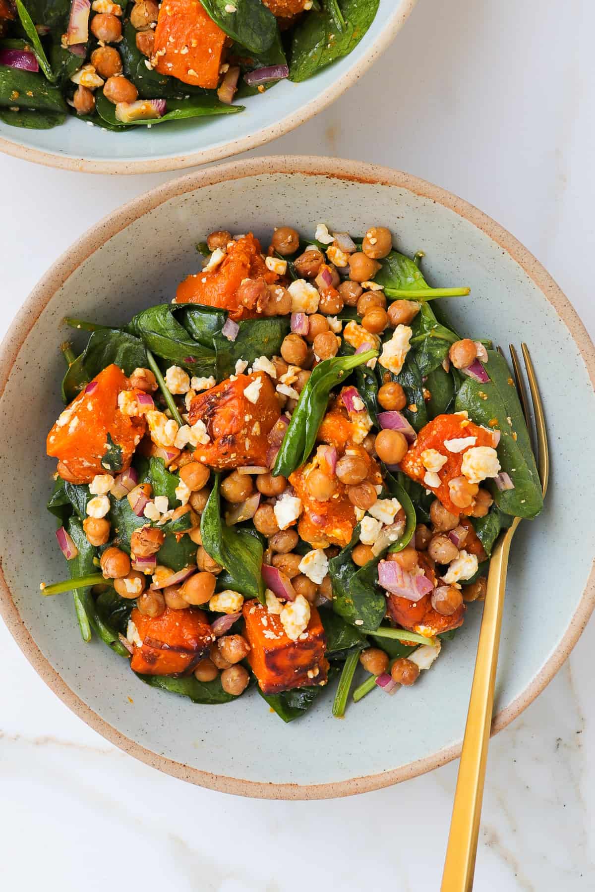 Chickpea pumpkin salad in a bowl with a gold fork.