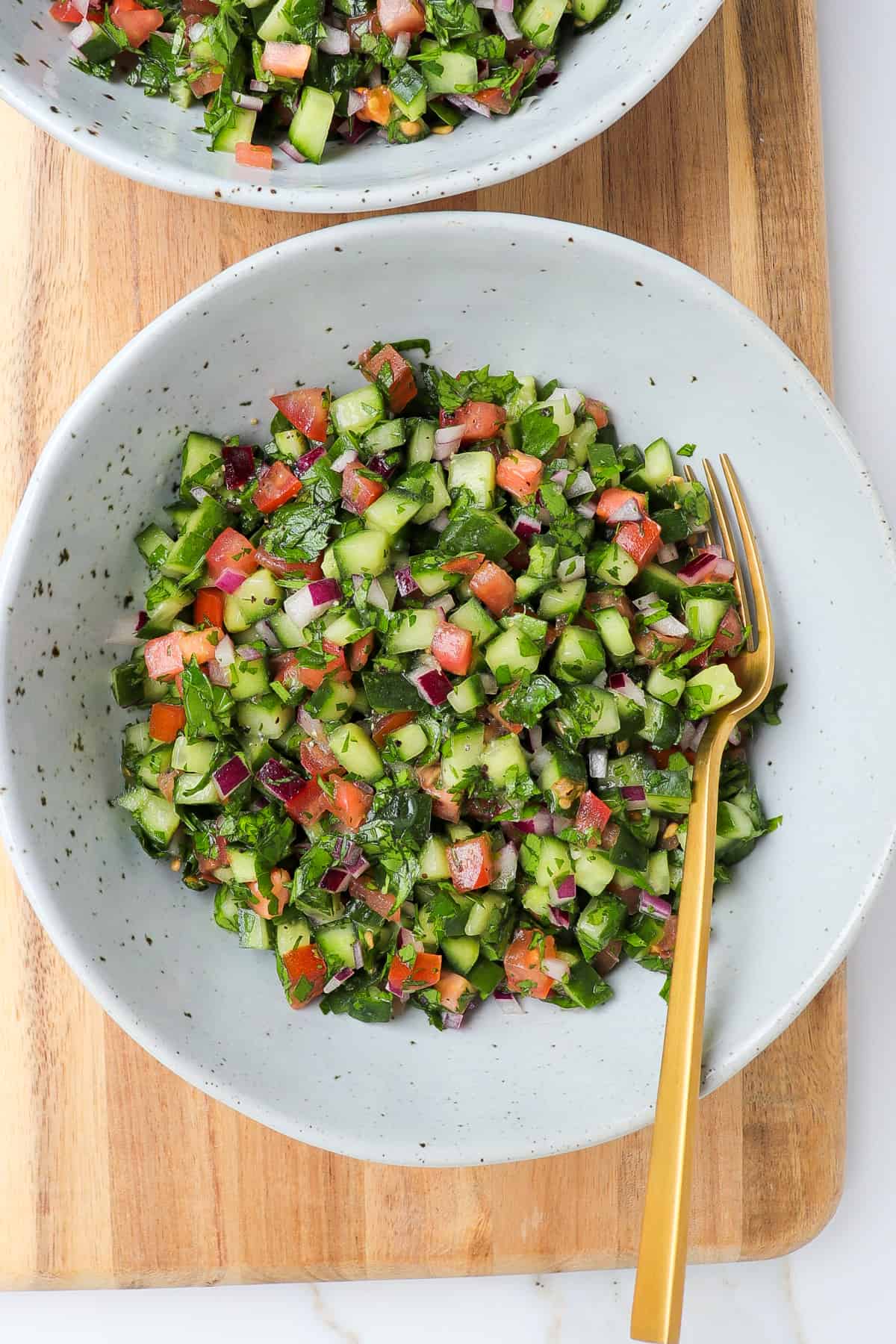 Jerusalem salad served in a bowl on wooden board.