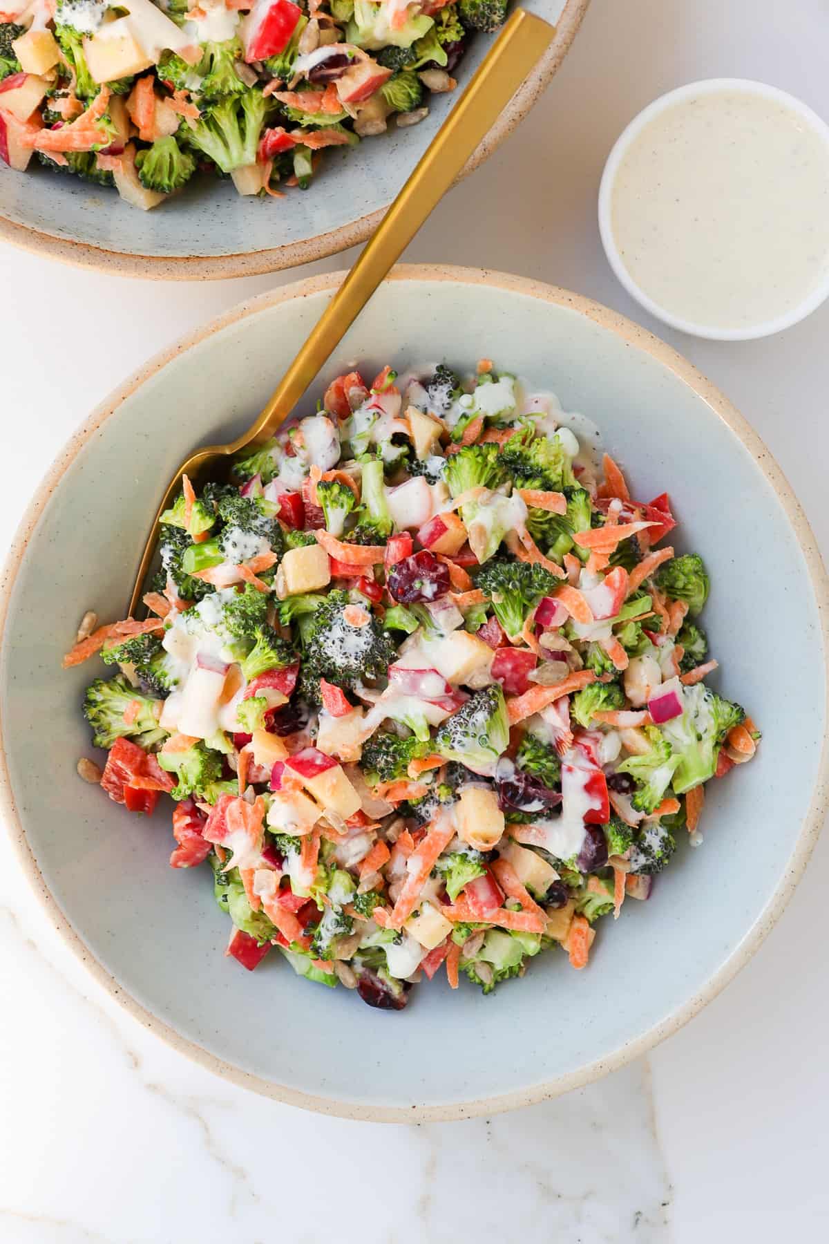 Broccoli crunch salad in a bowl with a gold fork.