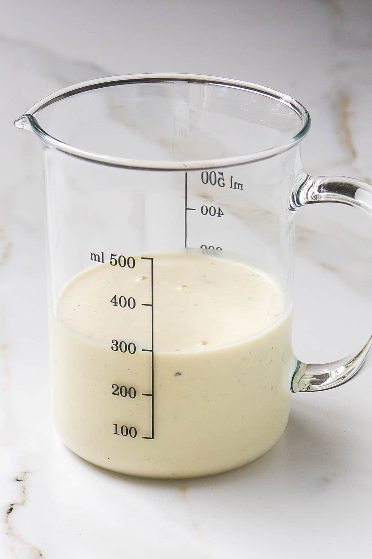 Yoghurt tahini dressing in a measuring jug.