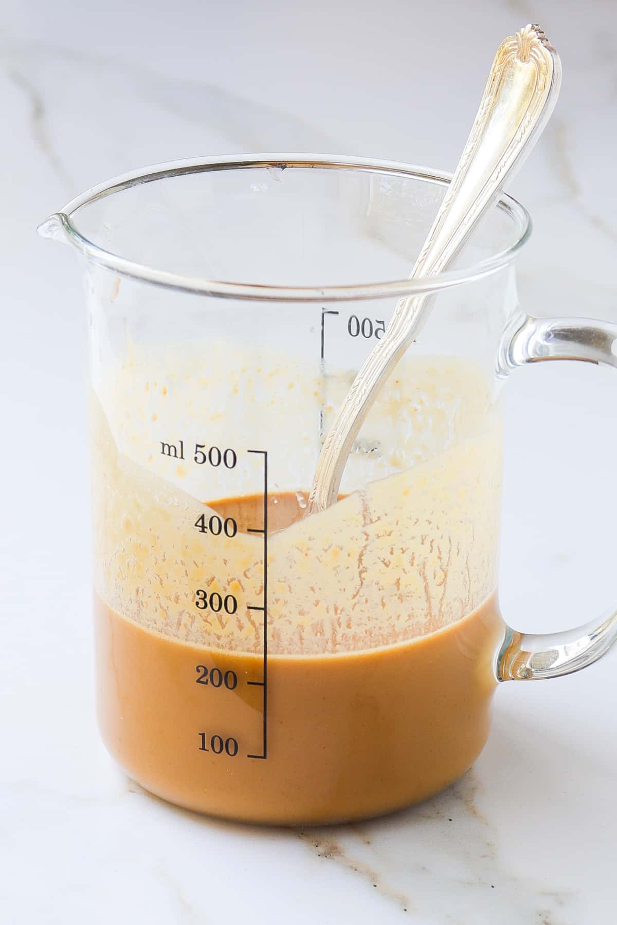 Side shot of the ginger peanut dressing in a measuring cup.