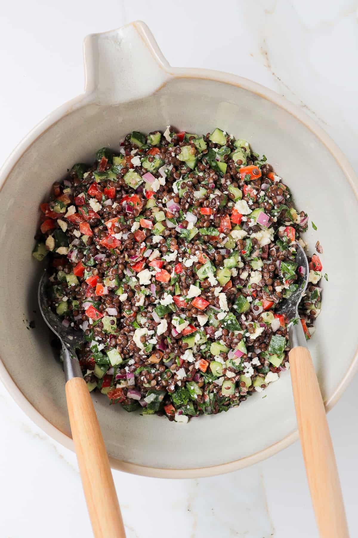 Black lentil salad in a mixing bowl with wooden spoons.