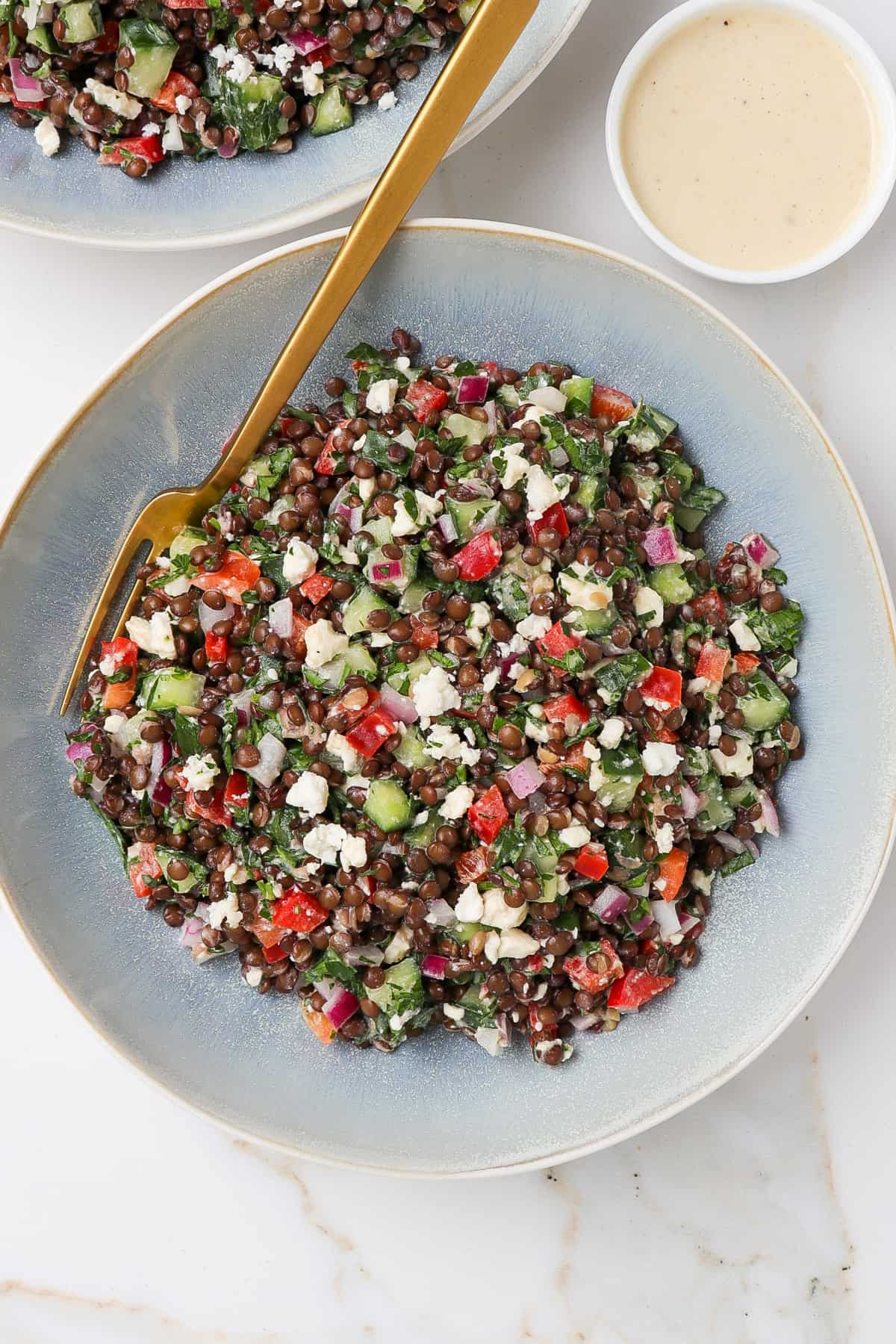 Salad in a blue bowl with a gold fork.