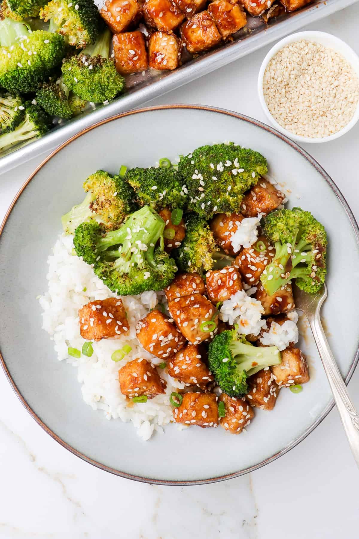 Honey garlic tofu in a bowl mixed up with roasted broccoli and rice.