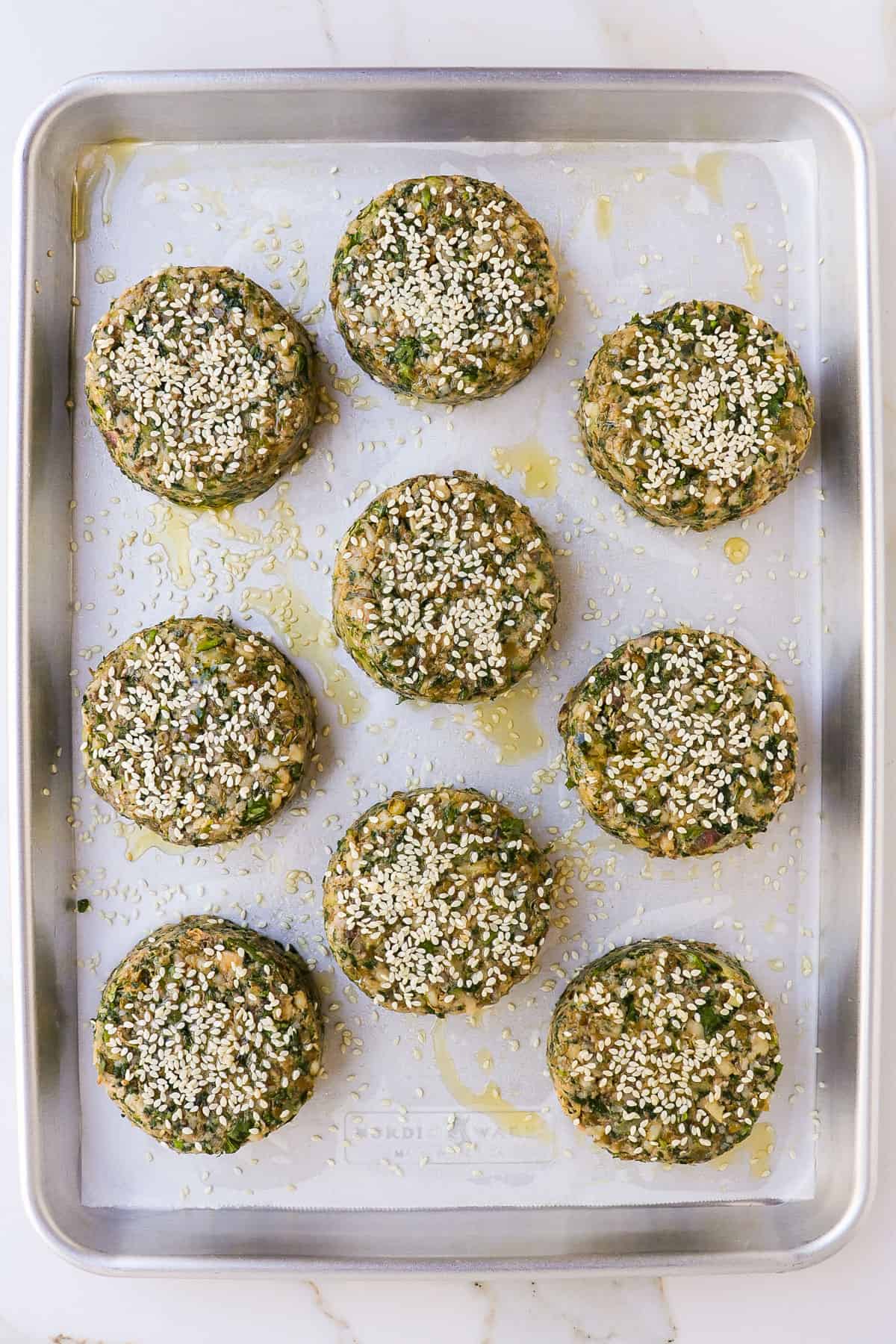 Uncooked mung bean burgers on baking sheet.