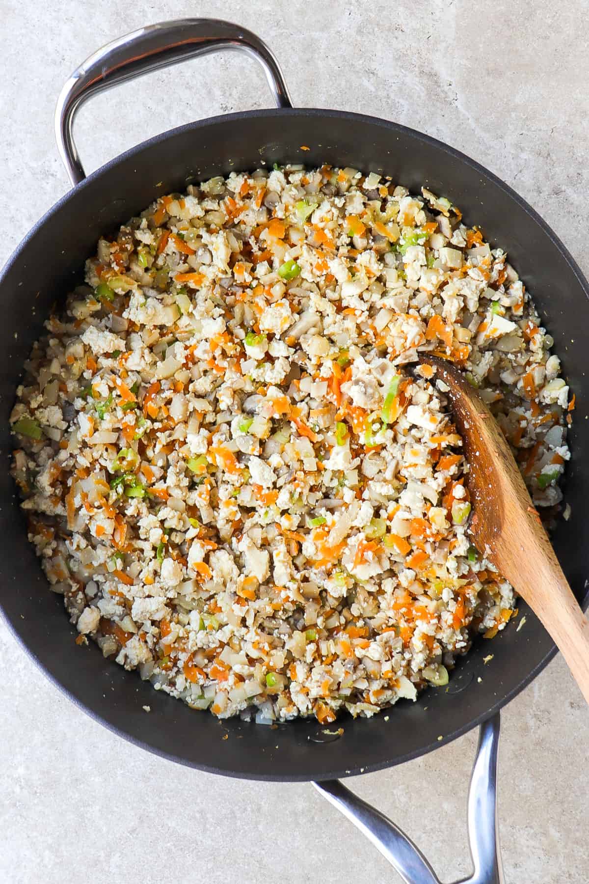 Tofu veggie filling in a pan with a wooden spoon.