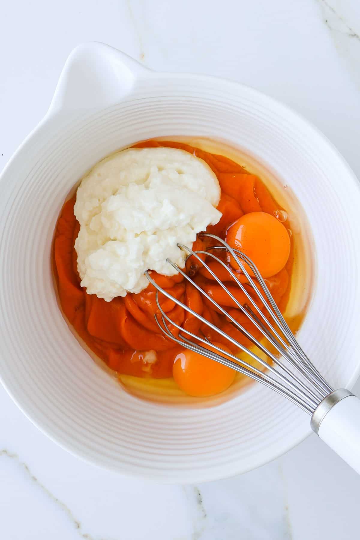 Wet ingredients in a mixing bowl with a whisk.
