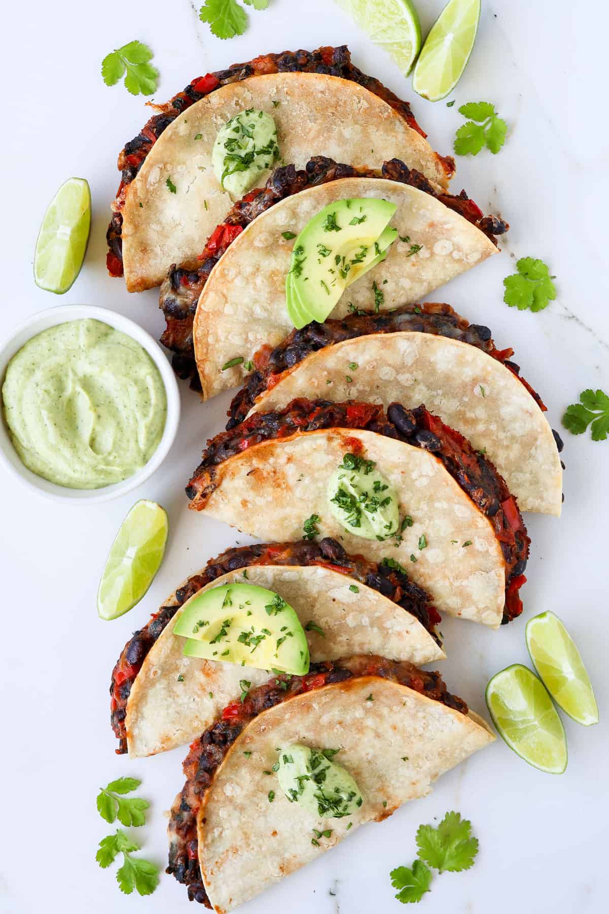 Crispy black bean tacos topped with avocado and crema.