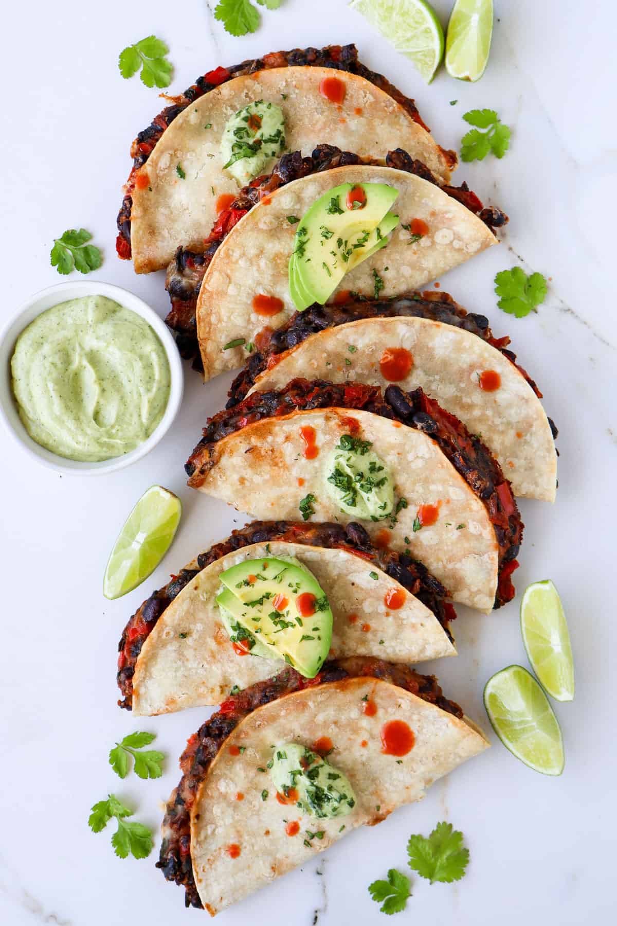 Crispy black bean tacos topped with avocado, crema and hot sauce.
