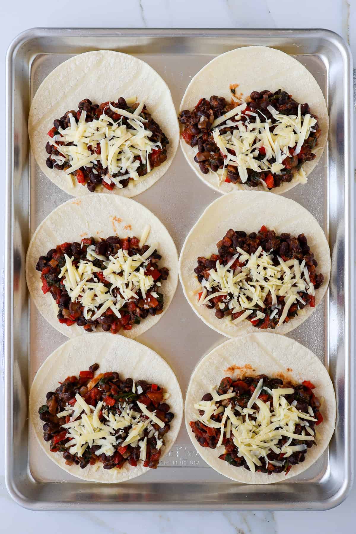 Tortillas topped with the black bean filling and cheese.