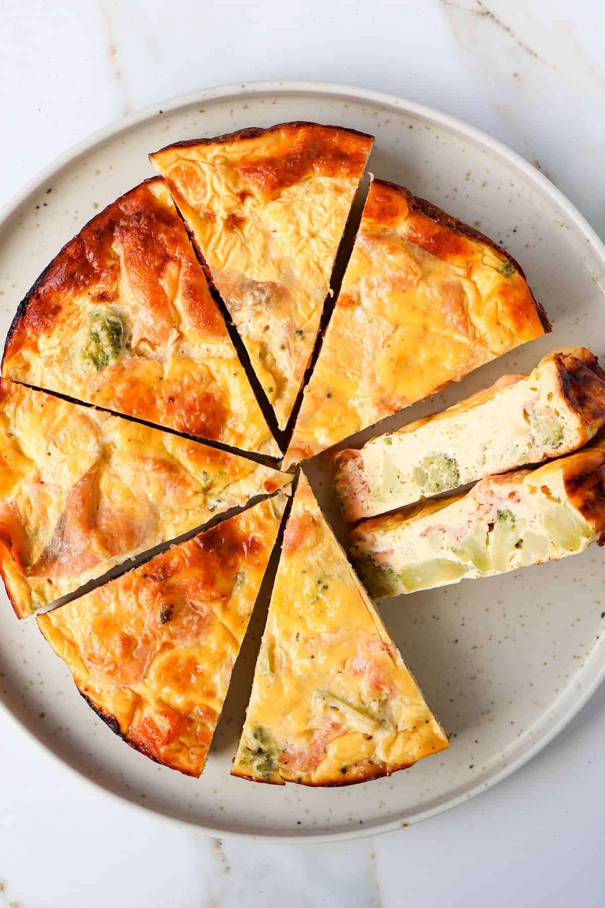 Side shot of salmon quiche on a plate.