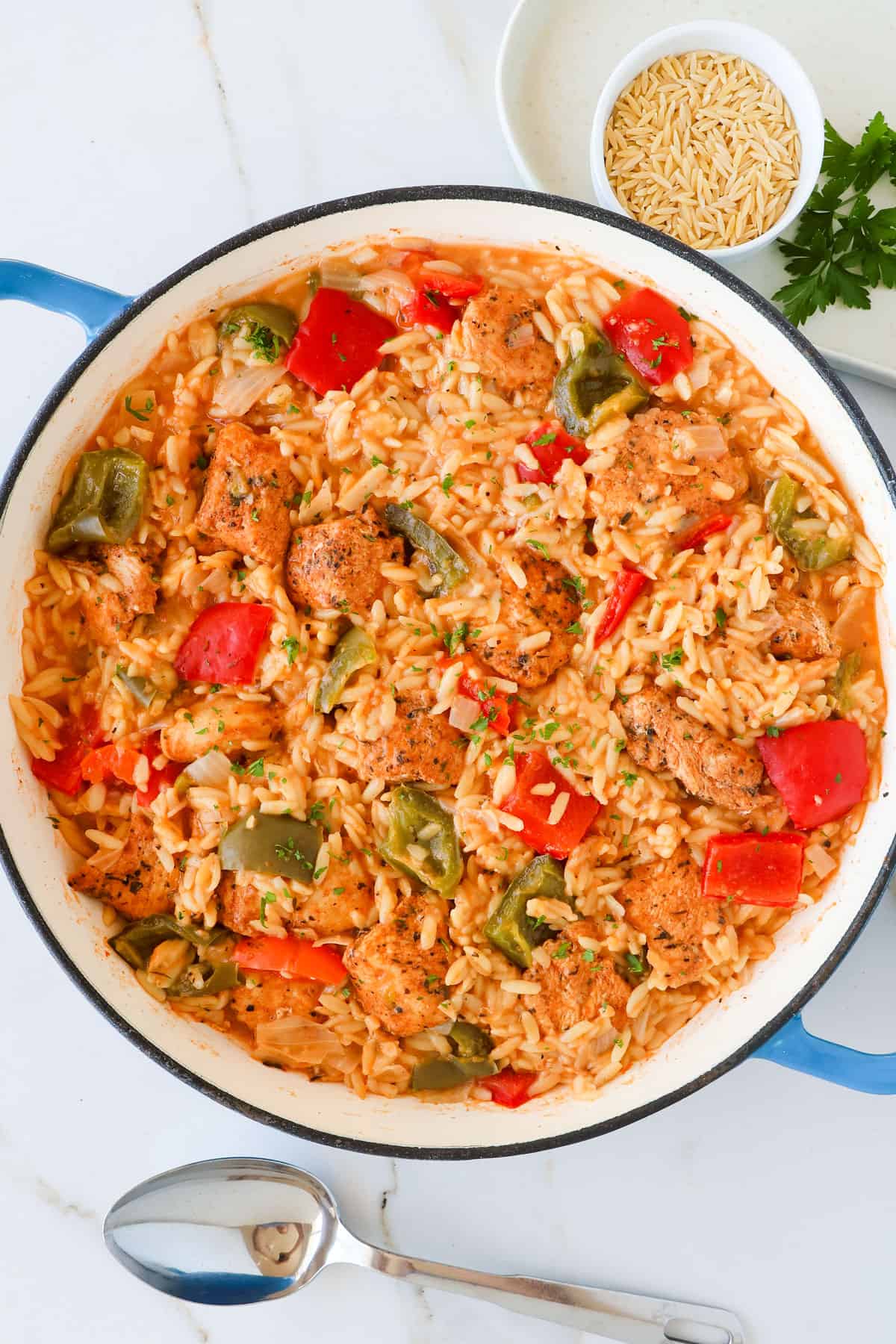 Cajun chicken orzo served with spoon.