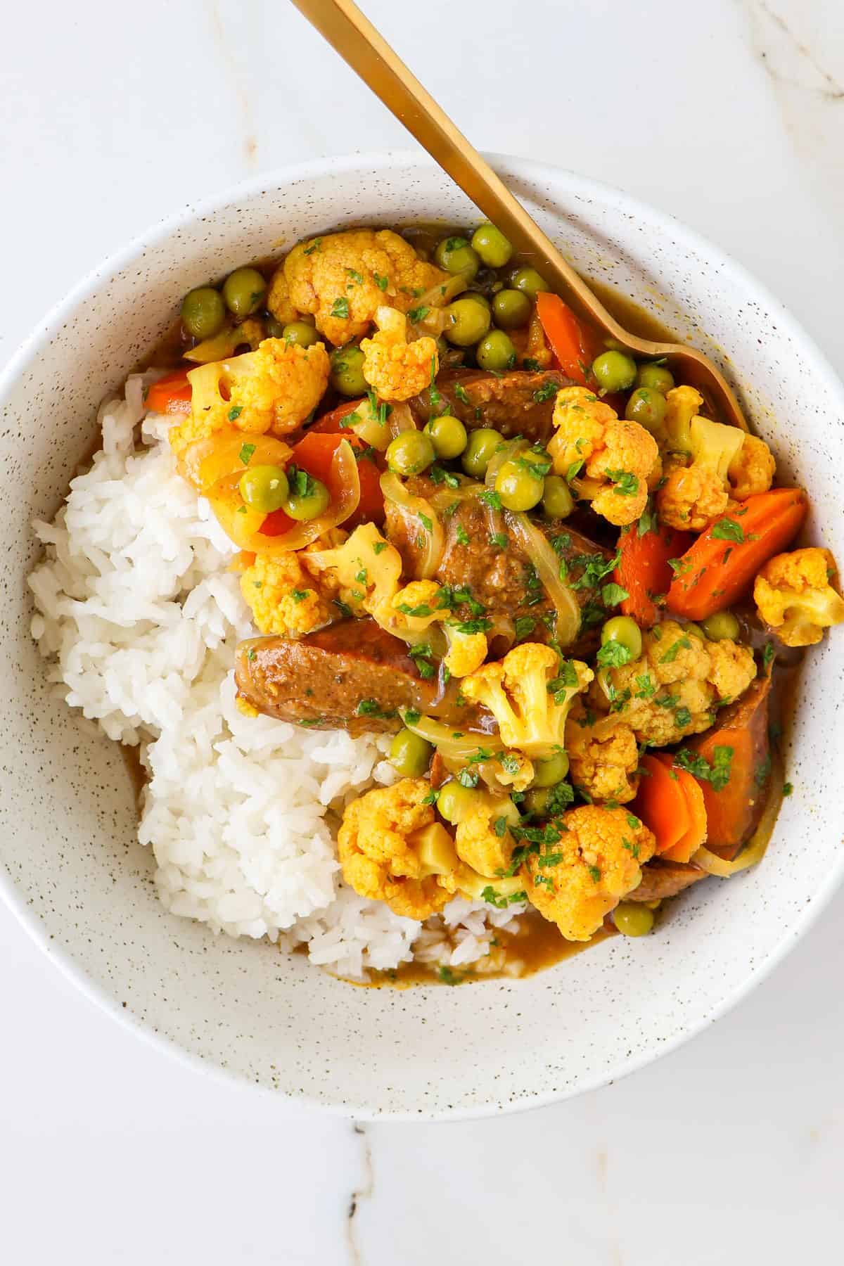 Sausage curry served in a bowl with rice.