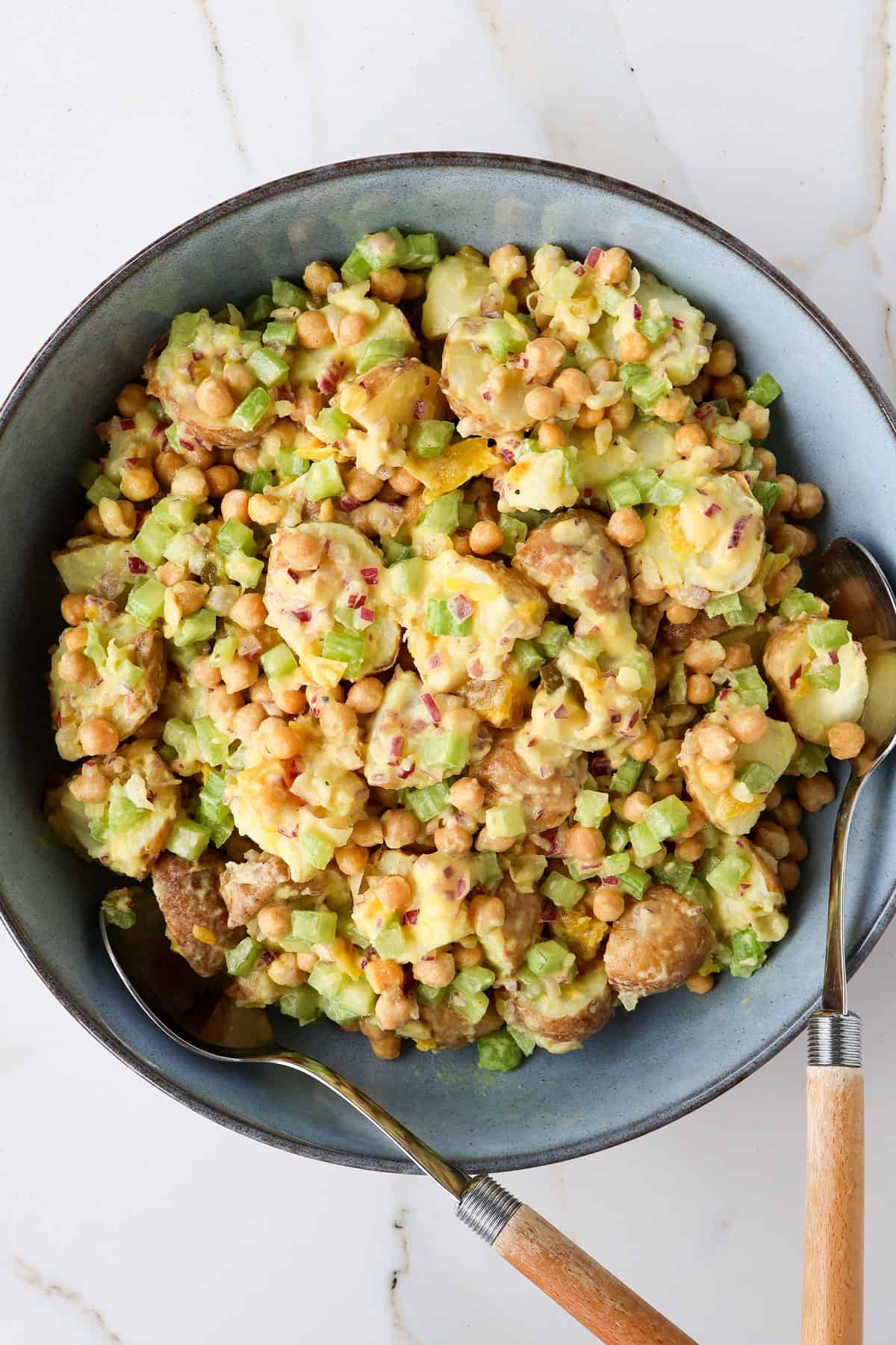 Chickpea potato salad with two wooden spoons.