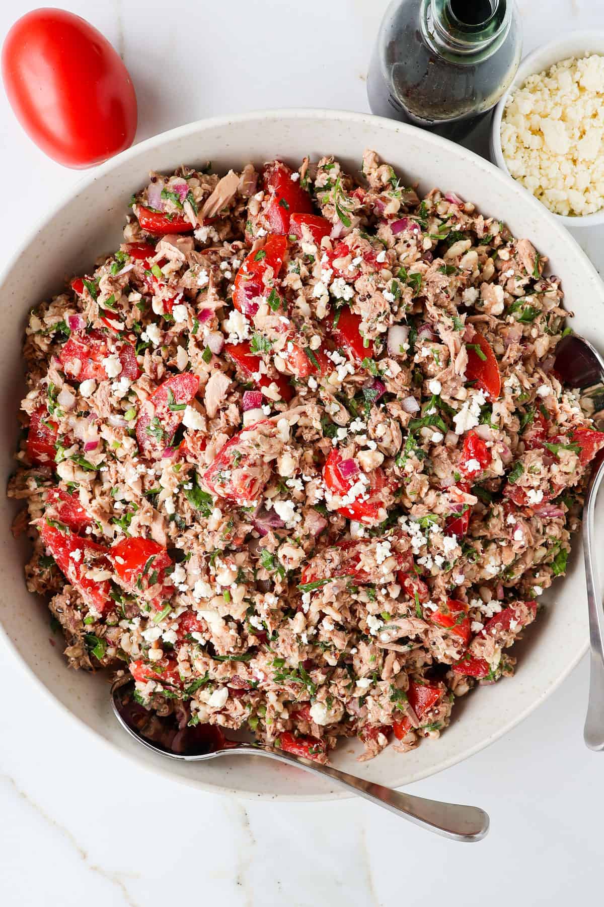 Tuna tomato salad in a bowl with two spoons.