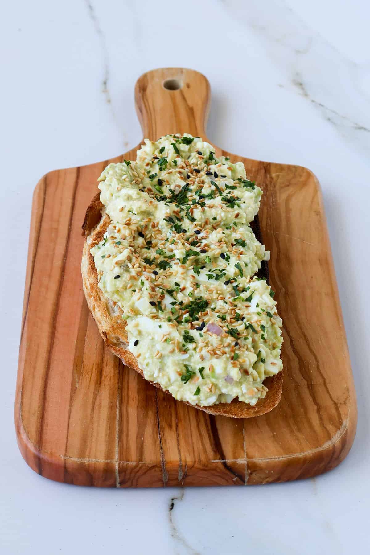 Side shot of cottage cheese avocado toast on a wooden board.