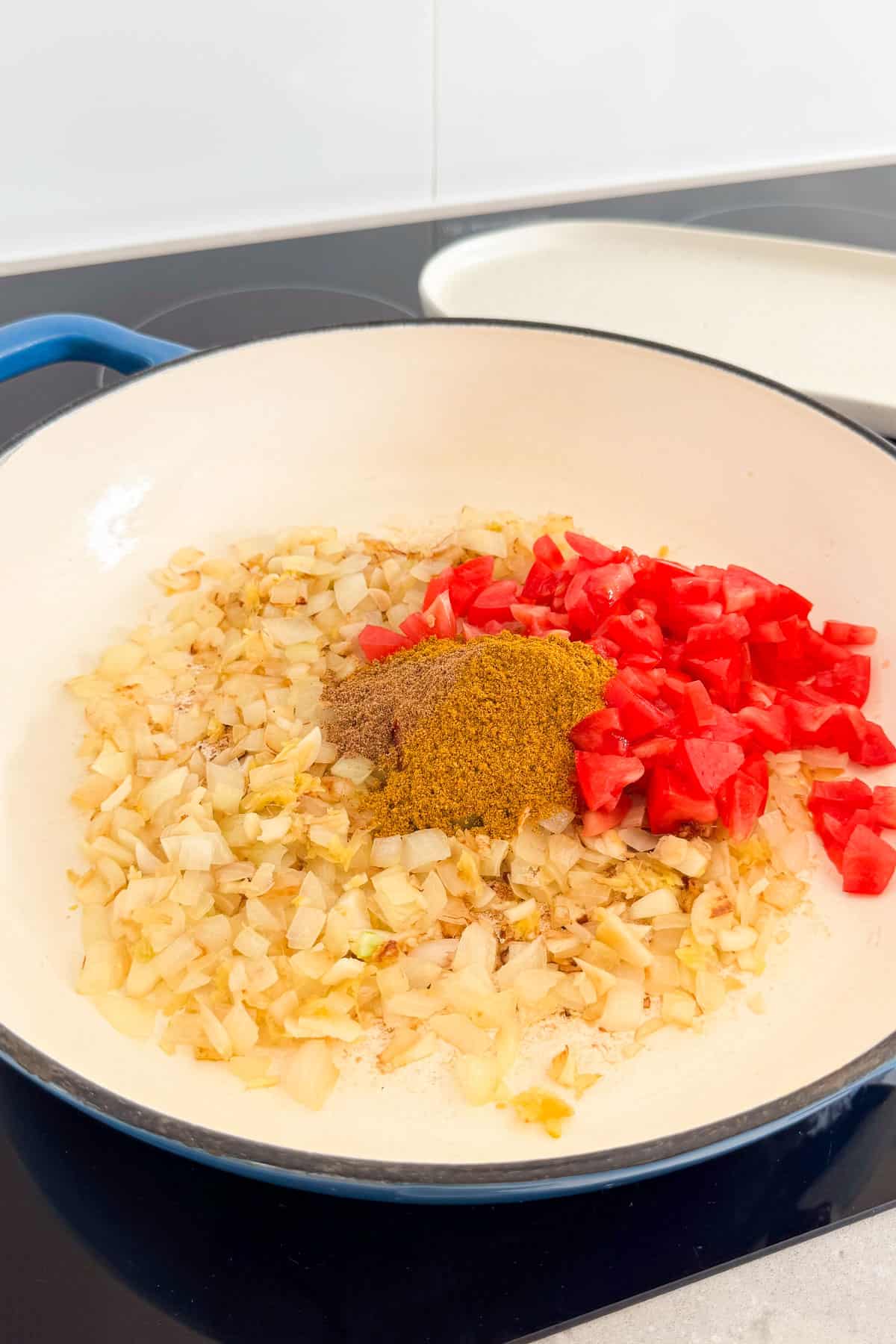 Curry spices and tomatoes added to the pan.
