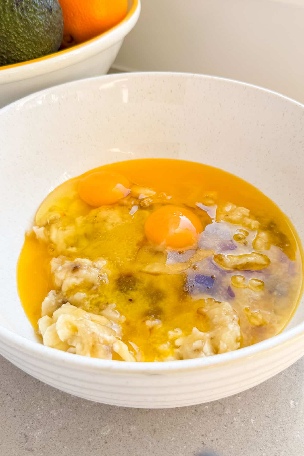 Mashed bananas, eggs, butter and vanilla in a bowl.