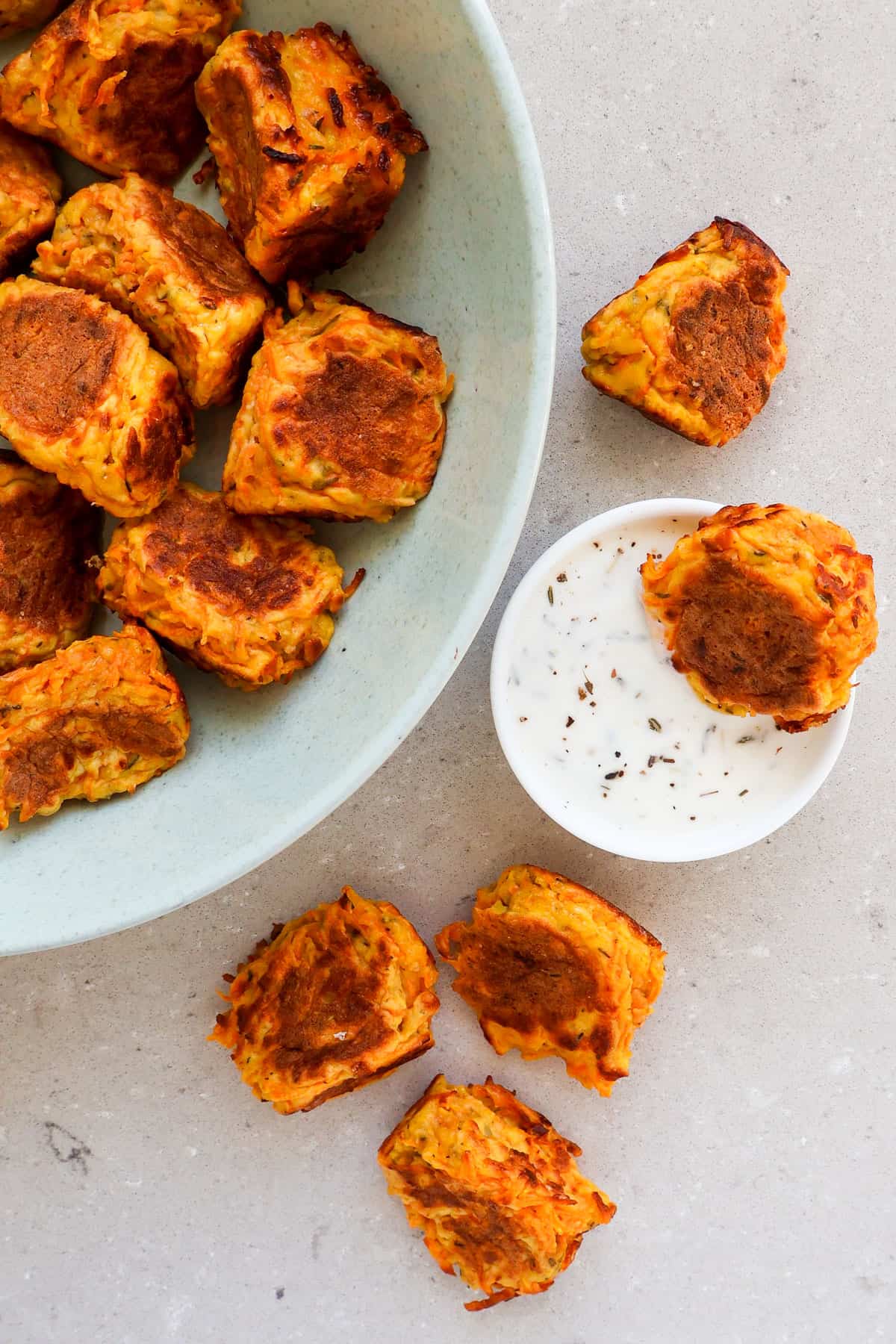 Fritters dipped in yoghurt and on bench.